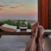 Photo of a woman's feet sticking out of a bath next to a drink and book